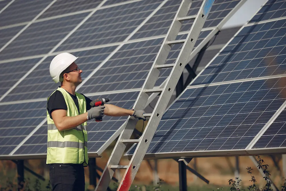 Solar technician inspecting rooftop solar panels using ladder for maintenance in Kerala